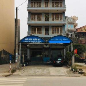 a building with a blue awning and a car parked in front at Xuân Mỹ Hostel Bãi Cháy in Ha Long