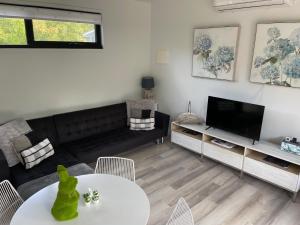a living room with a couch and a tv at Farm Stay POPLAR Cottage at Wilindi Estate in Tyabb