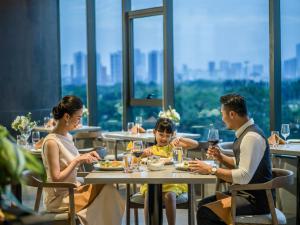 una familia sentada en una mesa en un restaurante en Fraser Residence Hanoi en Hanoi