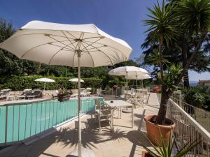 un patio con mesas y sombrillas junto a una piscina en Duca Del Mare - Hotel Di Nardo group, en Massa Marittima