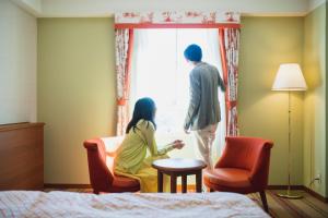 a man and woman sitting in a hotel room looking out the window at Hotel Nikko Huis Ten Bosch in Sasebo
