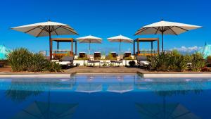 - une piscine avec des tables, des parasols et des chaises dans l'établissement Blue Margouillat Seaview Hotel-RELAIS & CHATEAUX, à Saint-Leu