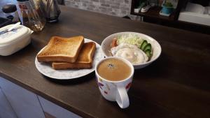 einen Tisch mit einem Teller Toast und einer Tasse Kaffee in der Unterkunft ゲストハウスのスタジオ５１ in Sasebo