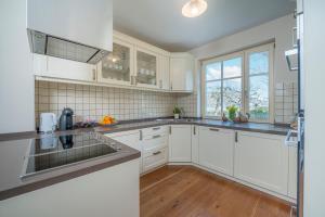 una cocina con armarios blancos y electrodomésticos de acero inoxidable en Villa Rory, en Bled