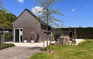 a small brick house with a tree in the yard at Bed en wellness de Heyde in Veghel