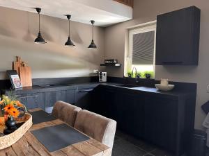 a kitchen with black cabinets and a dining table at Bed en wellness de Heyde in Veghel