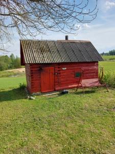 eine rote Scheune, die auf einem Grasfeld sitzt in der Unterkunft Marija in Krāslava