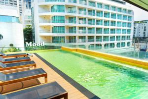 a swimming pool in front of a building at Mood Hotel Pattaya in Pattaya