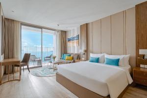 Cette chambre comprend un grand lit et une grande fenêtre. dans l'établissement OceanDream Panorama Luxury Suites, à Nha Trang