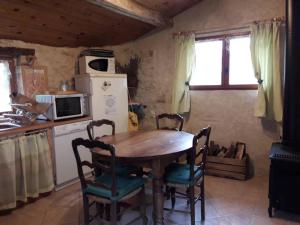 uma cozinha com uma mesa e cadeiras de madeira e um frigorífico em gîtes de Combelcau, le Pigeonnier em Flaugnac