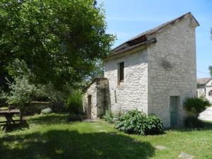 um velho edifício de pedra com um banco num quintal em gîtes de Combelcau, le Pigeonnier em Flaugnac