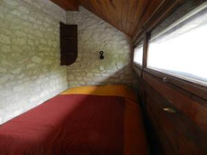 um quarto com uma cama de arco-íris numa parede de pedra em gîtes de Combelcau, le Pigeonnier em Flaugnac