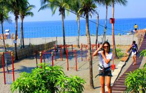 a woman standing on a rope swing at the beach at Bakasyunan Resort and Conference Center - Zambales in Iba