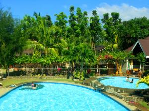 a pool at a resort with people in it at Bakasyunan Resort and Conference Center - Zambales in Iba