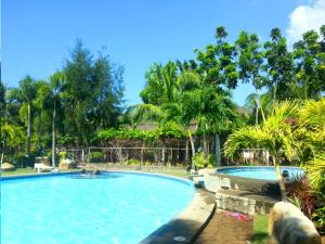 a swimming pool in a resort with people in it at Bakasyunan Resort and Conference Center - Zambales in Iba