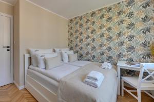 ein Schlafzimmer mit einem weißen Bett und Handtüchern darauf in der Unterkunft Downtown Apartments Gdynia Śląska in Gdynia