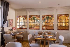 a restaurant with tables and chairs and stained glass windows at Hôtel Restaurant Le Kastelberg, The Originals Boutique in Andlau