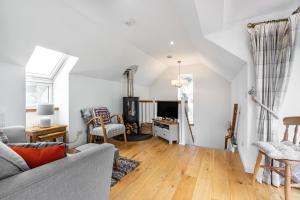 a living room with a couch and a tv at Urquhart Bay Croft in Drumnadrochit