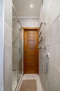 ein Badezimmer mit einer Dusche und einer Holztür in der Unterkunft Murnieku residence in Riga