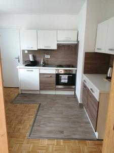 cocina pequeña con armarios blancos y fogones en Wohnung Gretl, en Bayerisch Eisenstein