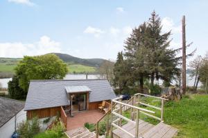 a small house with a deck and a staircase at Urquhart Bay Croft in Drumnadrochit