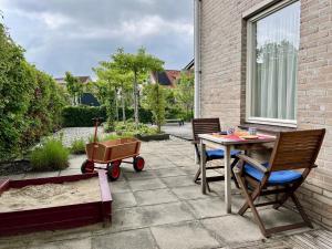 een patio met een tafel en stoelen en een kinderwagen bij Hello Zeeland - Vakantiehuis Zwin 182 in Breskens