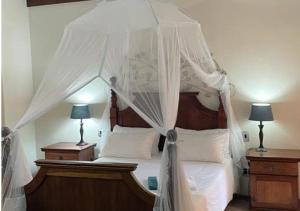 a bedroom with a canopy bed with white sheets and pillows at Moon Landscape Self Catering in Swakopmund