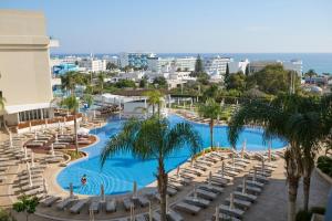 a view of a pool with chairs and palm trees at Sunrise Oasis Hotel & Waterpark in Protaras