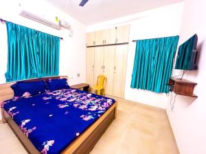 a bedroom with a bed with blue sheets and blue curtains at Paradise Elite Rooms in Madurai