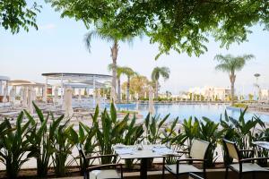 - une table et des chaises en face de la piscine dans l'établissement Sunrise Oasis Hotel & Waterpark, à Protaras