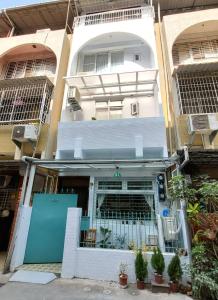 un edificio blanco con una puerta azul y algunas plantas en Good Stay, en Tainan