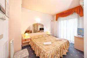 Habitación de hotel con cama y espejo en Hotel Villa Luisa, en Lignano Sabbiadoro