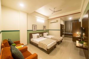 a hotel room with two beds and a couch at Olive Hotel Electronic City by Embassy Group in Bengaluru
