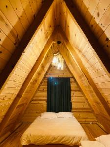 a bed in a wooden attic room with a window at Bungi dağ evleri in Rize