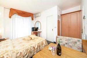 una camera con letto e tavolo con una bottiglia di vino di Hotel Villa Luisa a Lignano Sabbiadoro