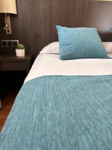 a bed with a green blanket and a blue pillow at Hotel 1948 Manresa in Manresa