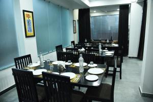 comedor con mesa y sillas con platos y botellas de agua en The Altruist Business Stays- New Town, Kolkata en Calcuta