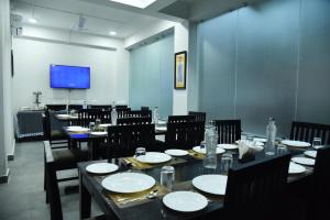 comedor con mesas y sillas y TV de pantalla plana en The Altruist Business Stays- New Town, Kolkata en Calcuta