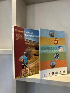 dwie książki na półce z mężczyzną na rowerze w obiekcie Villa Pandolfi w mieście Pescara