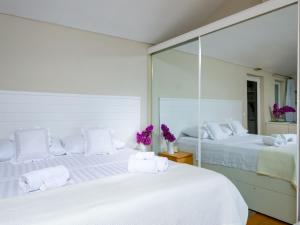 a white bedroom with two beds with mirrors at Villa Lola in Lopud