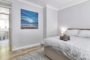 Modern Spacious 2 Bedroom Apartment in Brentwood في Shenfield: غرفة نوم بيضاء مع سرير و لوحة على الحائط