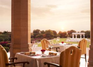 a restaurant with tables and chairs with the sun setting at Umaid Bhawan Palace Jodhpur in Jodhpur