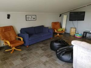 a living room with a blue couch and two chairs at Vindsvåning i Harrström in Korsnäs