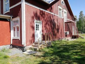 a red house with a white door and stairs on it at Vindsvåning i Harrström in Korsnäs