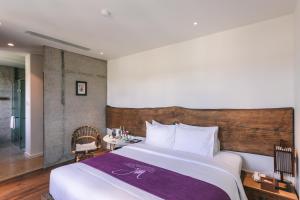 1 dormitorio con 1 cama grande con manta morada en JM Boutique Hotel en Phu Quoc