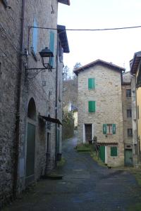 um beco entre dois edifícios de pedra com persianas verdes em RB Della Torre em Porretta Terme