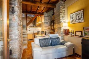 a living room with a white couch and a stone wall at Villa Camelia Bianca in Barga