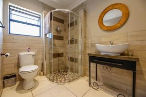 y baño con aseo, lavabo y ducha. en Touching Senses Garden Cottages, en Bloemfontein