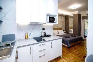 una cocina con armarios blancos y una cama en una habitación en LK Apartment -A- Metro Larissis 6' Walk - Athens, en Atenas