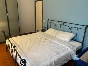 a bed with white sheets and a metal frame at Flat in Garden Residence resort, Malcesine, Italy (with heated pool) in Malcesine